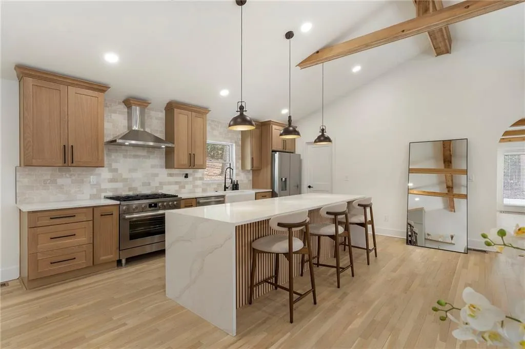 Kitchen featuring a breakfast bar area, stainless steel appliances, a center island, light wood-style floors, and lofted ceiling