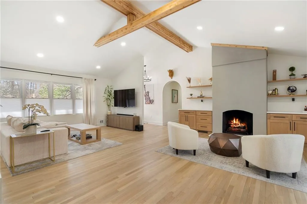 Living area featuring arched walkways, light wood finished floors, recessed lighting, and a fireplace