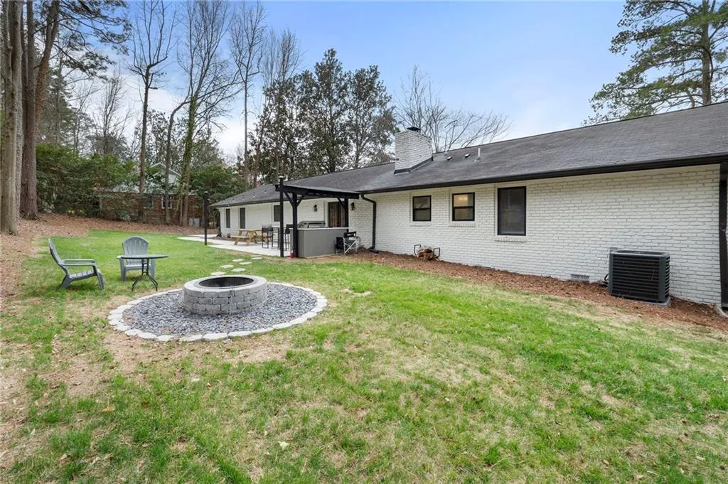 Rear view of house with a patio, a fire pit, brick siding, a chimney, and crawl space