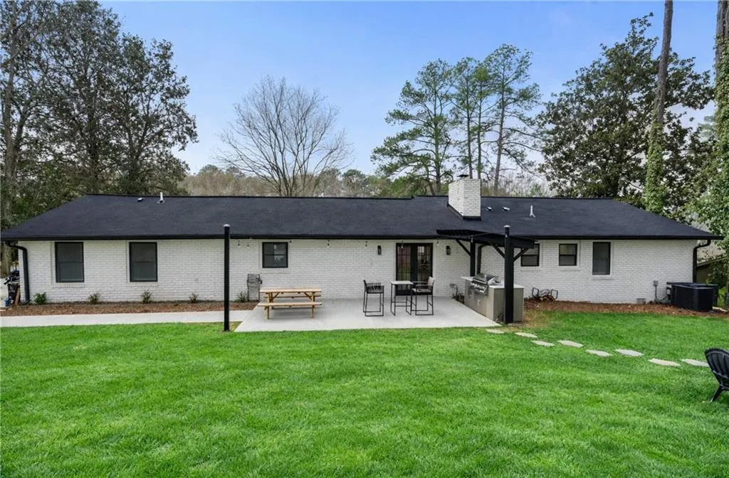 Back of house with a patio, a yard, a chimney, and brick siding