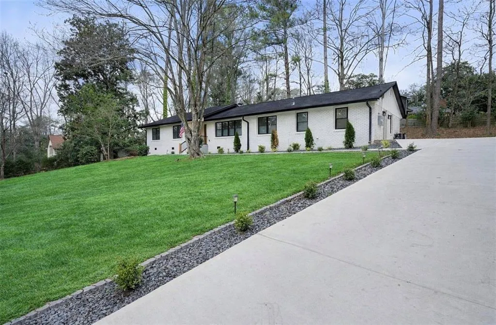 Single story home featuring a front yard, brick siding, driveway, and a garage