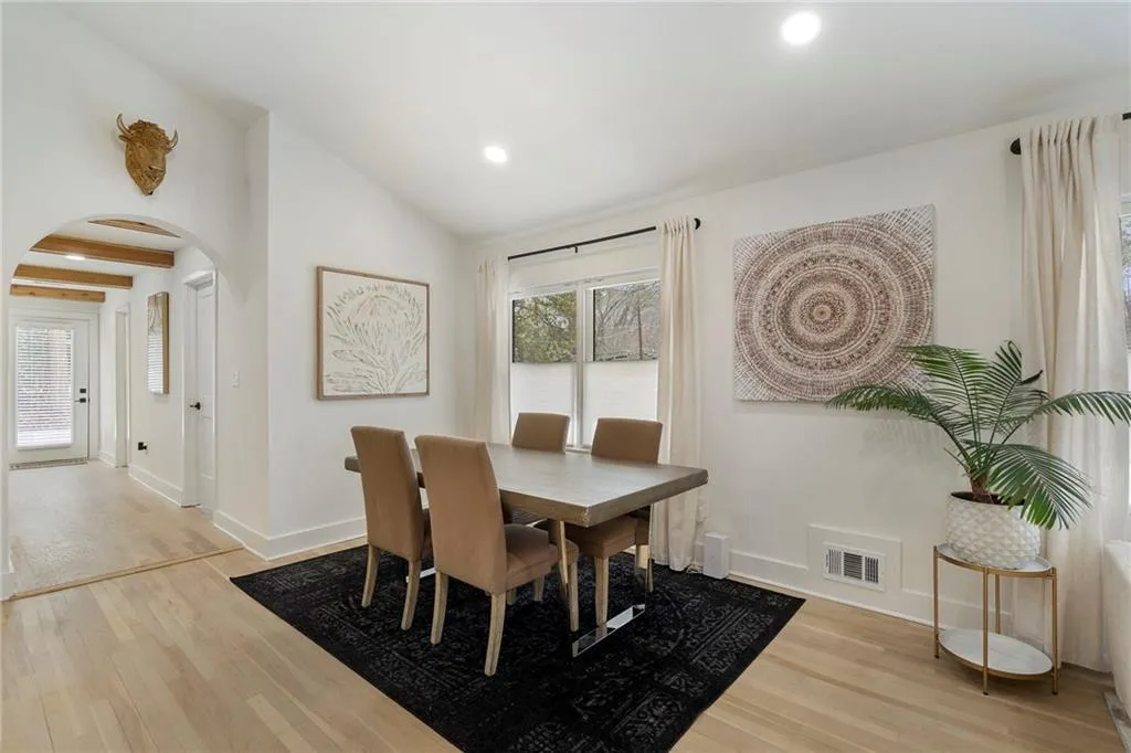 Dining room with arched walkways, light wood finished floors, vaulted ceiling, and recessed lighting
