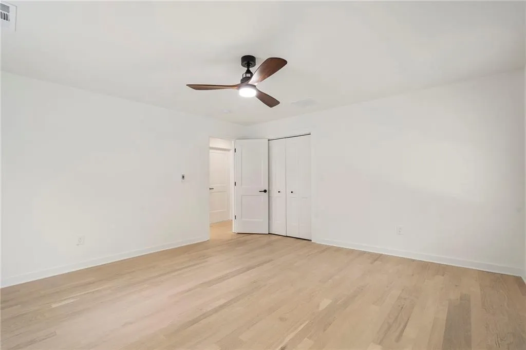 Unfurnished bedroom with light wood-style flooring, ceiling fan, and a closet