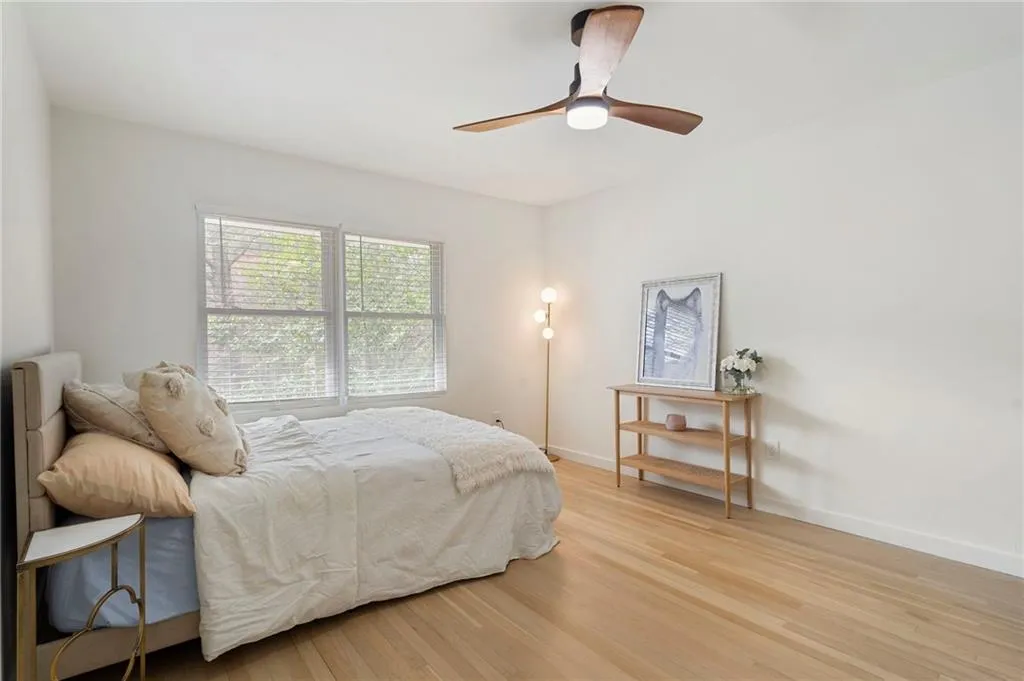 Bedroom with light wood-type flooring, ceiling fan, and radiator
