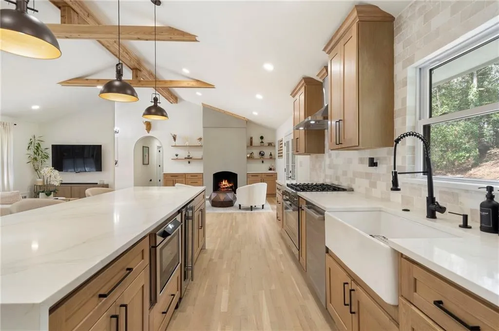 Kitchen featuring open floor plan, light stone counters, light wood finished floors, and a fireplace