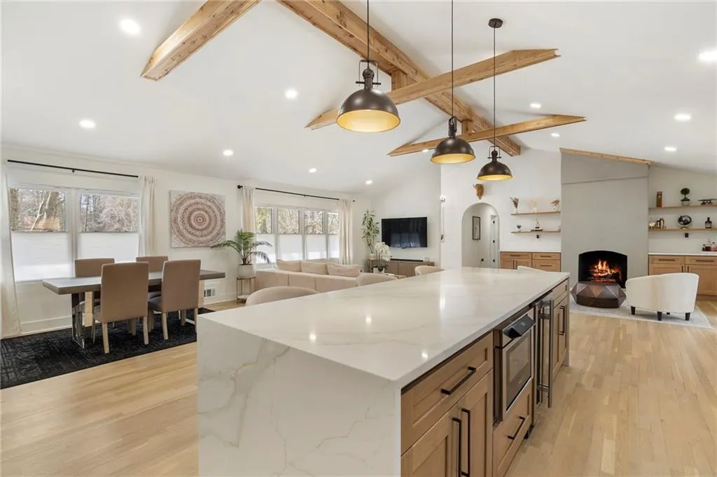Kitchen with open floor plan, light wood-style floors, hanging light fixtures, a center island, and light stone counters