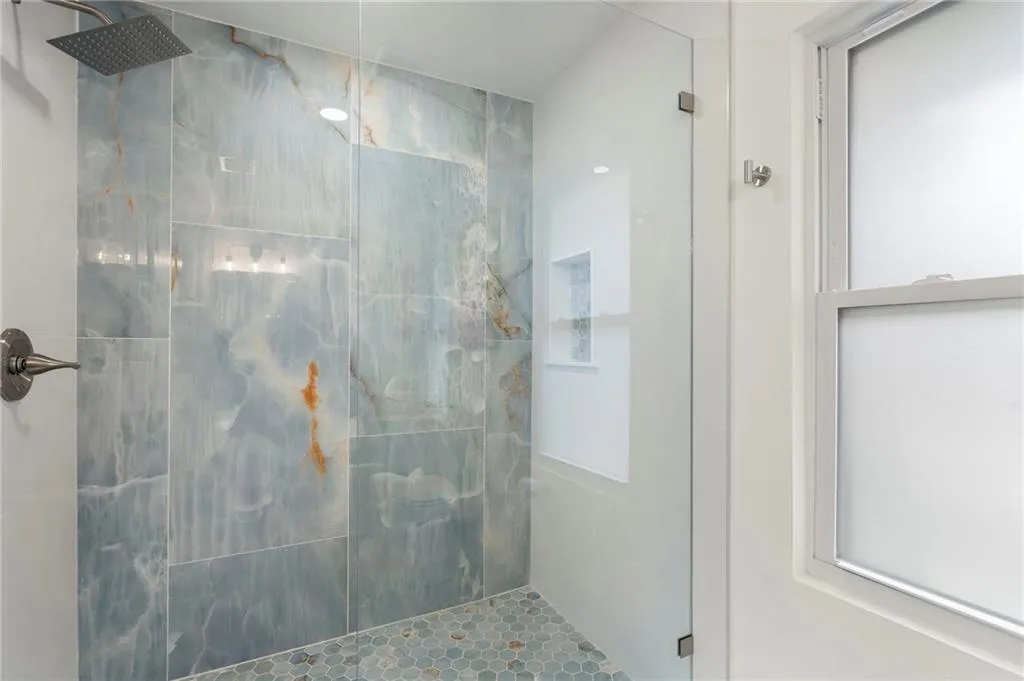 Full bath with a marble finish shower