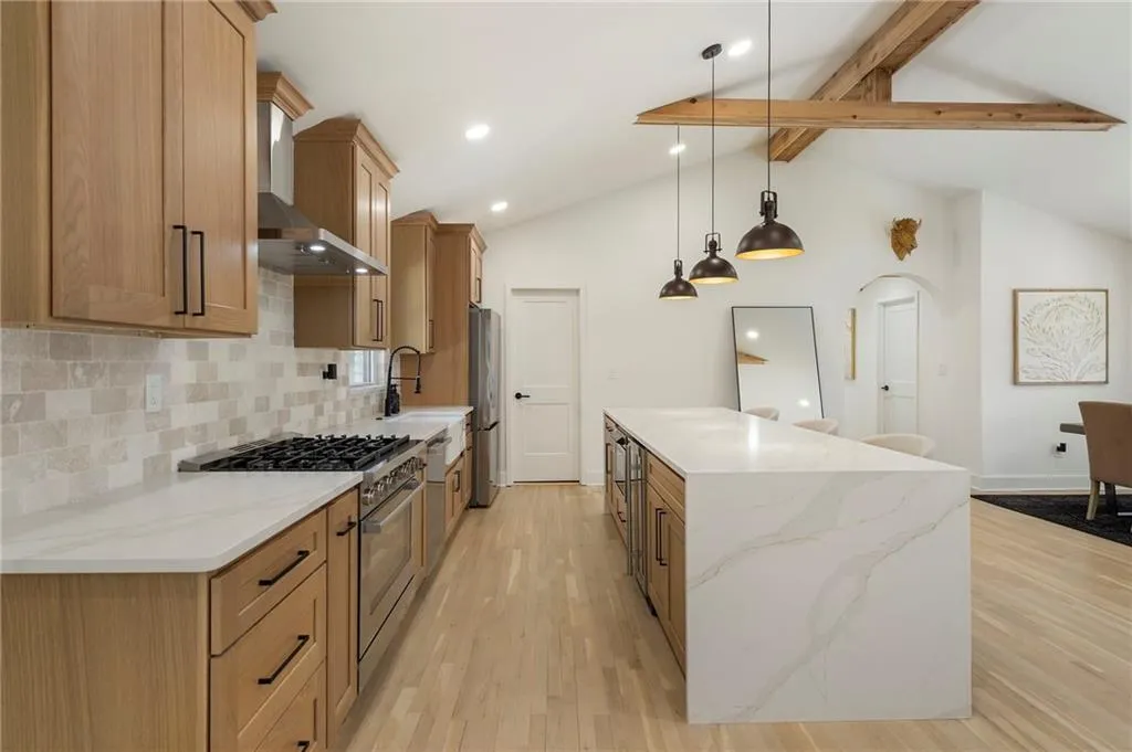 Kitchen featuring stainless steel appliances, backsplash, a center island, light wood-style floors, and light stone countertops