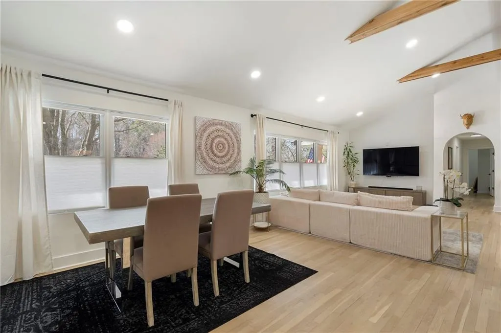 Dining area featuring arched walkways, recessed lighting, light wood-style floors, and lofted ceiling
