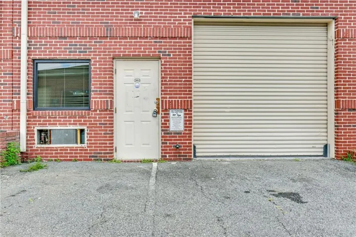 Brick exterior featuring a cream-colored roll-up door and an entry door