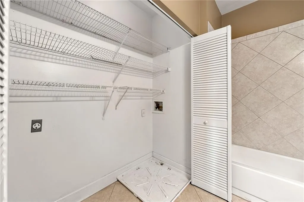 Laundry area with light tile patterned flooring, hookup for a washing machine, and electric dryer hookup