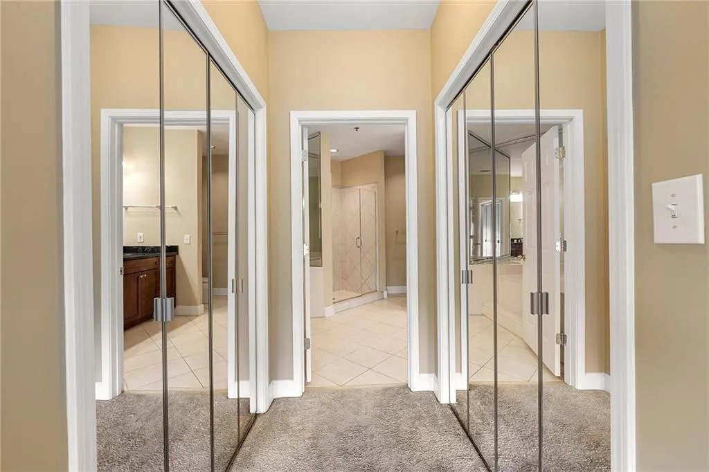 Hallway featuring light tile patterned flooring and light carpet