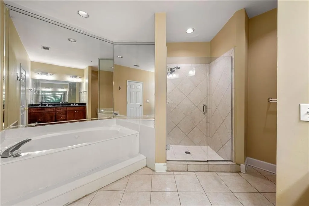 Full bathroom with a shower stall, a garden tub, light tile patterned flooring, vanity, and recessed lighting