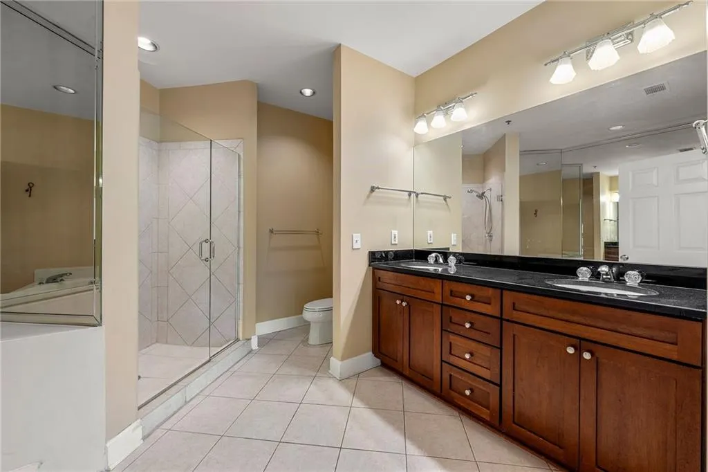 Full bathroom featuring light tile patterned flooring, a shower stall, double vanity, and recessed lighting