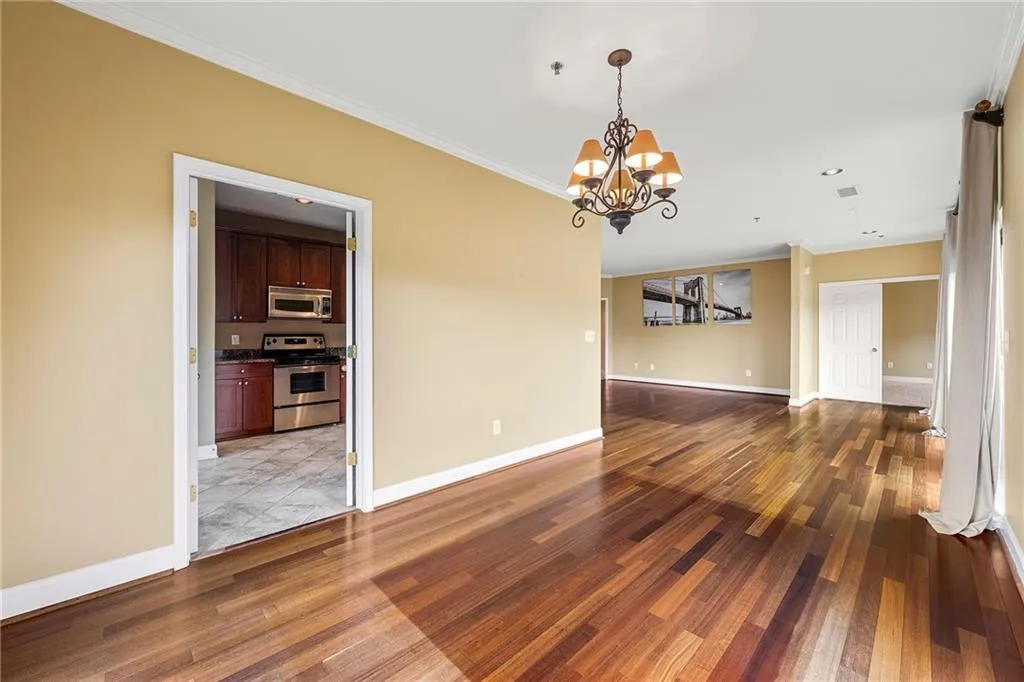 Unfurnished dining area with ornamental molding, dark wood finished floors, and a chandelier