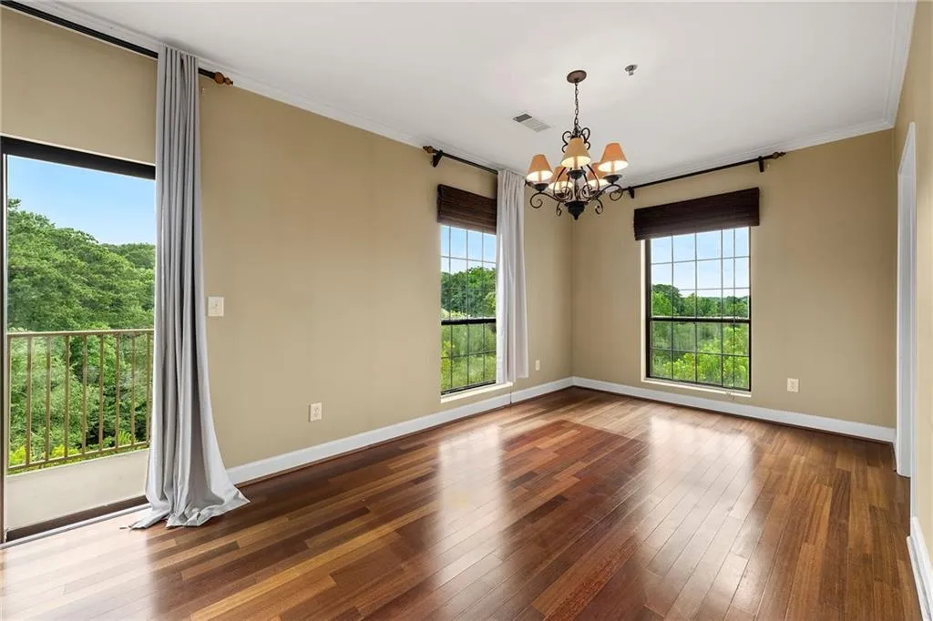 Empty room with hardwood / wood-style flooring, ornamental molding, and a chandelier