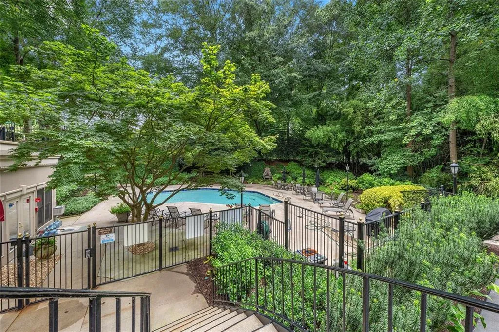 Community pool with a patio and view of wooded area