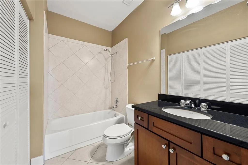 Bathroom with a closet, shower / bath combination, light tile patterned floors, and vanity