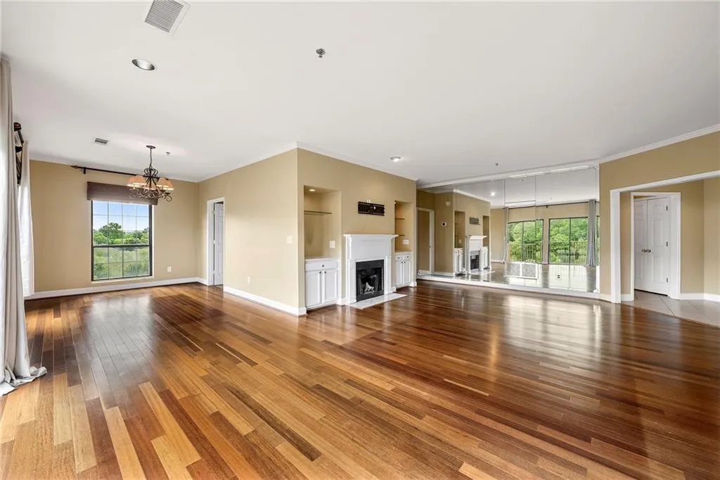 Unfurnished living room with a fireplace, ornamental molding, light wood-style flooring, and a chandelier