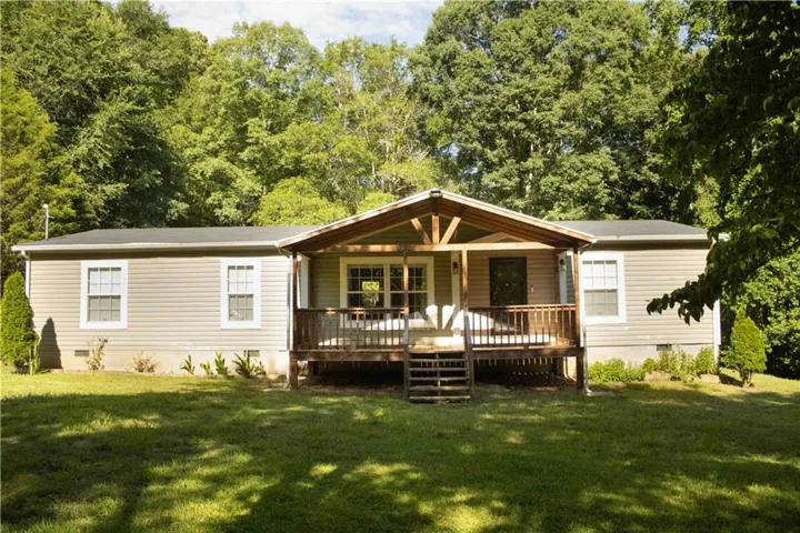 Front exterior featuring a covered porch with exposed wood beams, wood railing, and steps