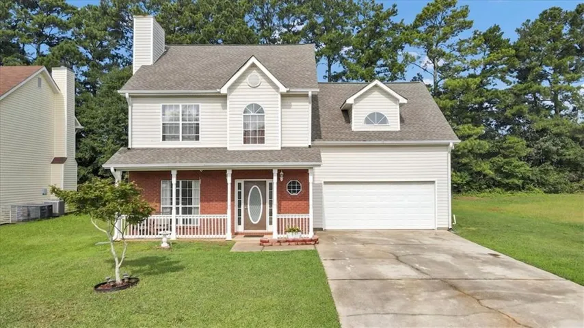 Two-story siding exterior with brick accents, covered front porch, attached garage, and a semicircular dormer window