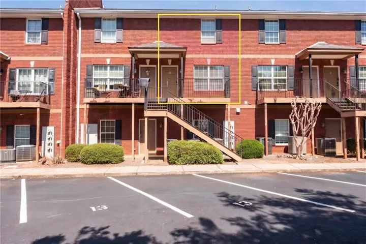 Brick facade with black shutters, covered entry with exterior stairs, and a private balcony
