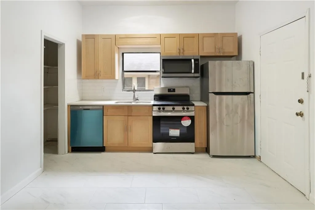 Kitchen with appliances with stainless steel finishes, light countertops, tasteful backsplash, and light marble finish floors