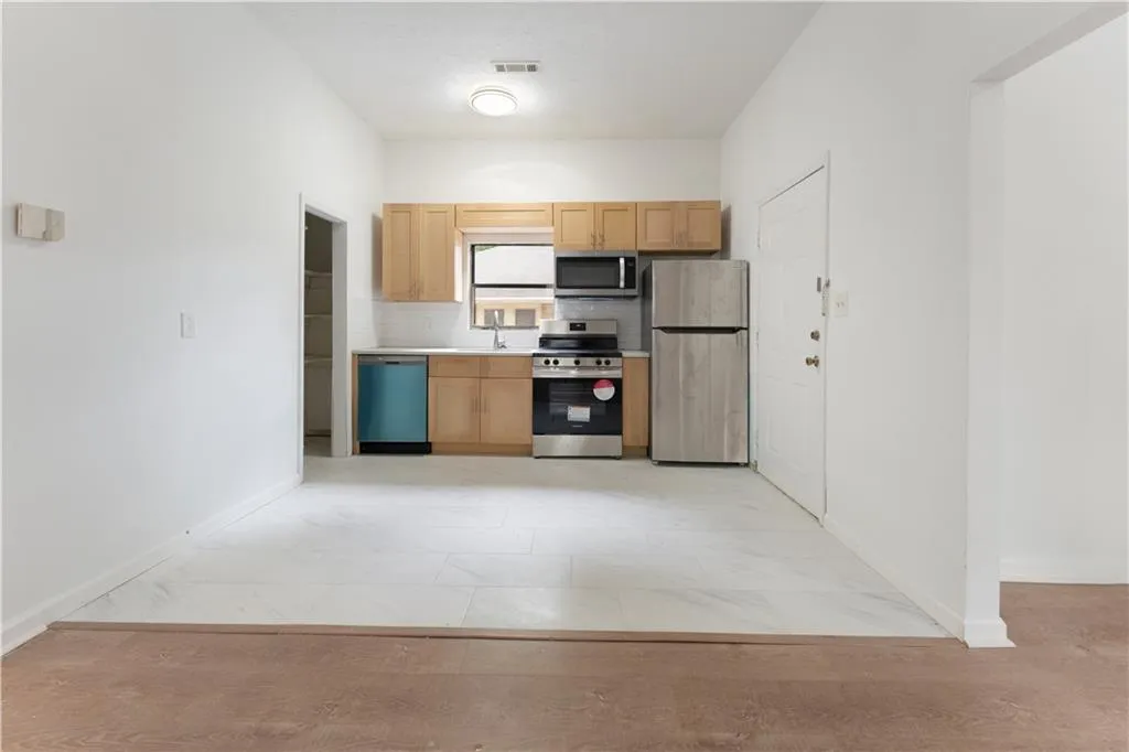 Kitchen with light countertops, appliances with stainless steel finishes, decorative backsplash, and light brown cabinetry