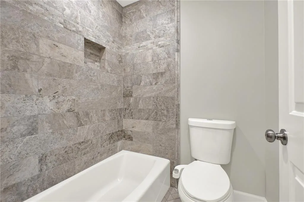 Bathtub with stone-look tile surround and integrated shower niche