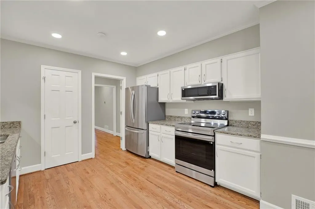 Kitchen featuring light wood-finish flooring, white cabinetry, and stone countertops