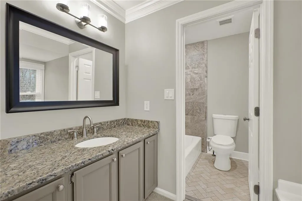 Bathroom featuring a single vanity with stone countertop, undermount sink, and brushed nickel faucet