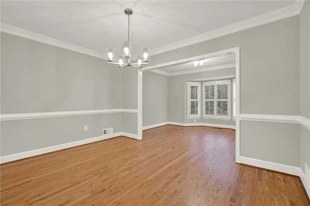 Dining room featuring newly refinished hardwood floors, new paint, crown and chair rail moulding, new chandelier with LED bulbs, and built ins.