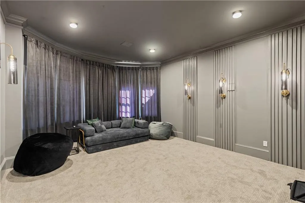 Home theater room with carpet floors and crown molding