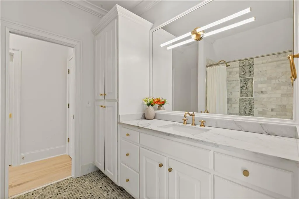 Full bathroom featuring a shower with shower curtain, vanity, light tile patterned floors, and crown molding