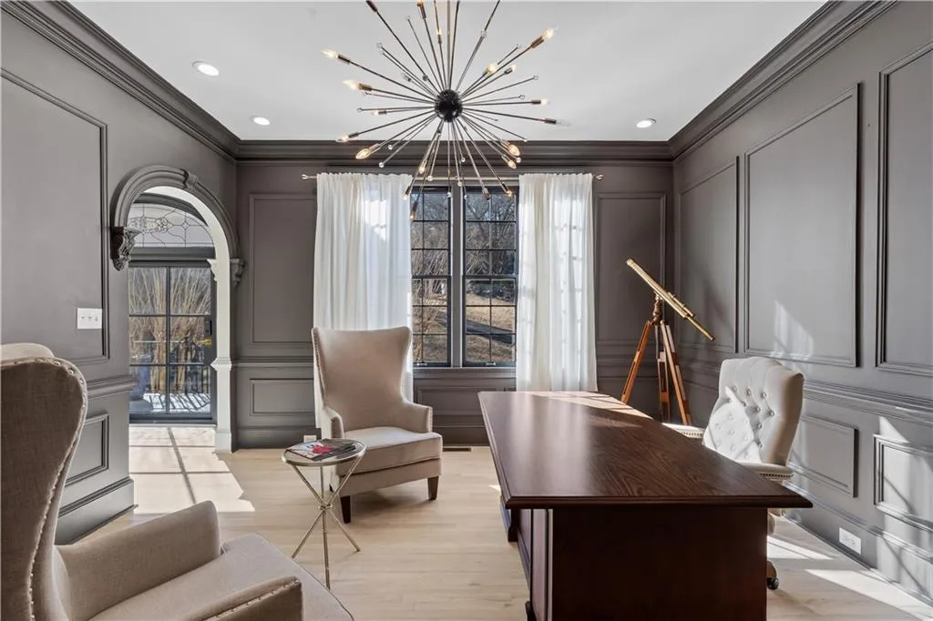 Office featuring a decorative wall, ornamental molding, hanging lights, light wood finished floors, and plenty of natural light