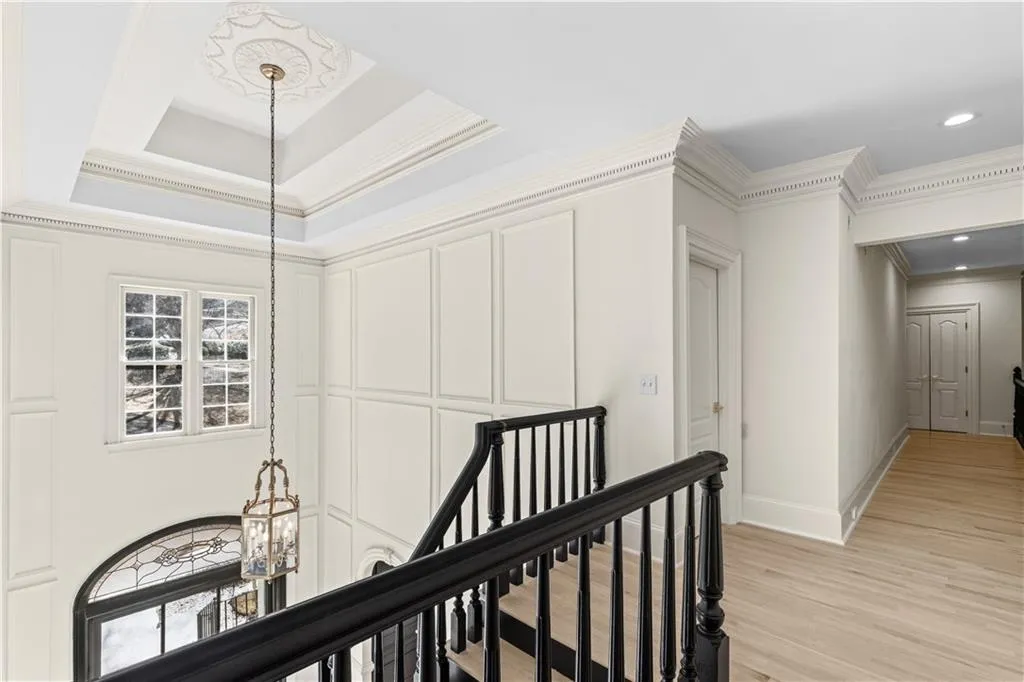 Hallway with an upstairs landing, crown molding, and light wood-type flooring
