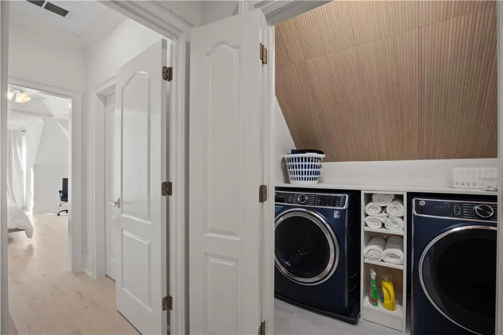 Laundry area featuring ornamental molding, light wood-type flooring, and washing machine and dryer