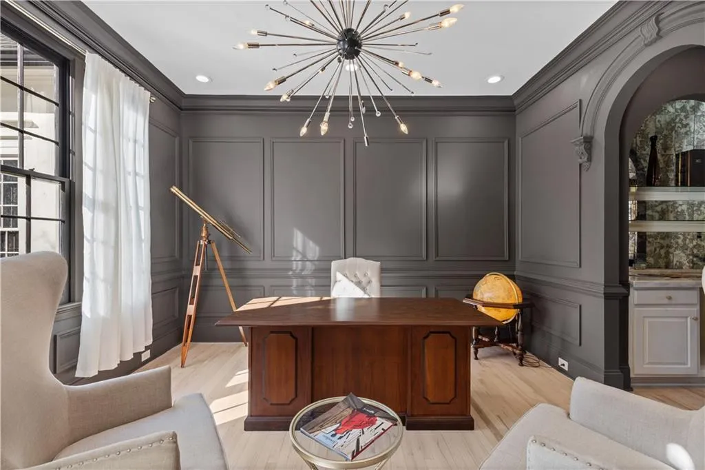 Home office with a decorative wall, arched walkways, ornamental molding, and a chandelier