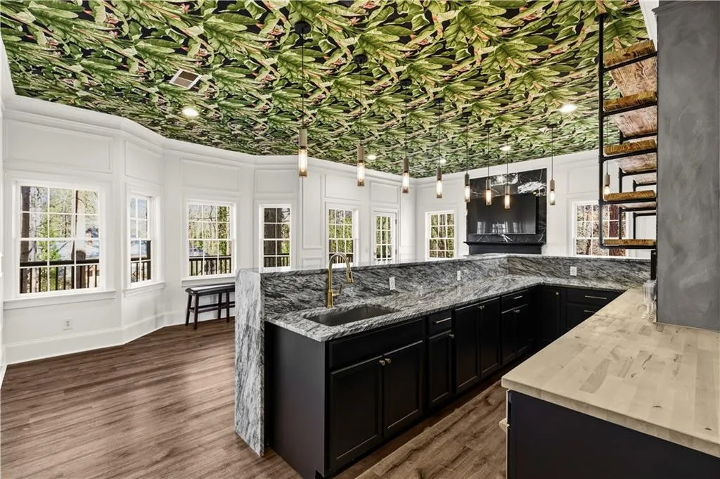 Kitchen featuring dark cabinets, plenty of natural light, dark wood-type flooring, and a decorative wall