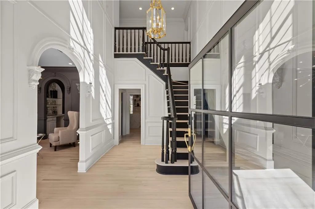 Foyer entrance featuring a decorative wall, arched walkways, a high ceiling, suspended lighting, and light wood-type flooring
