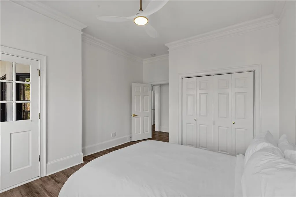 Bedroom with ornamental molding, dark wood finished floors, ceiling fan, and a closet