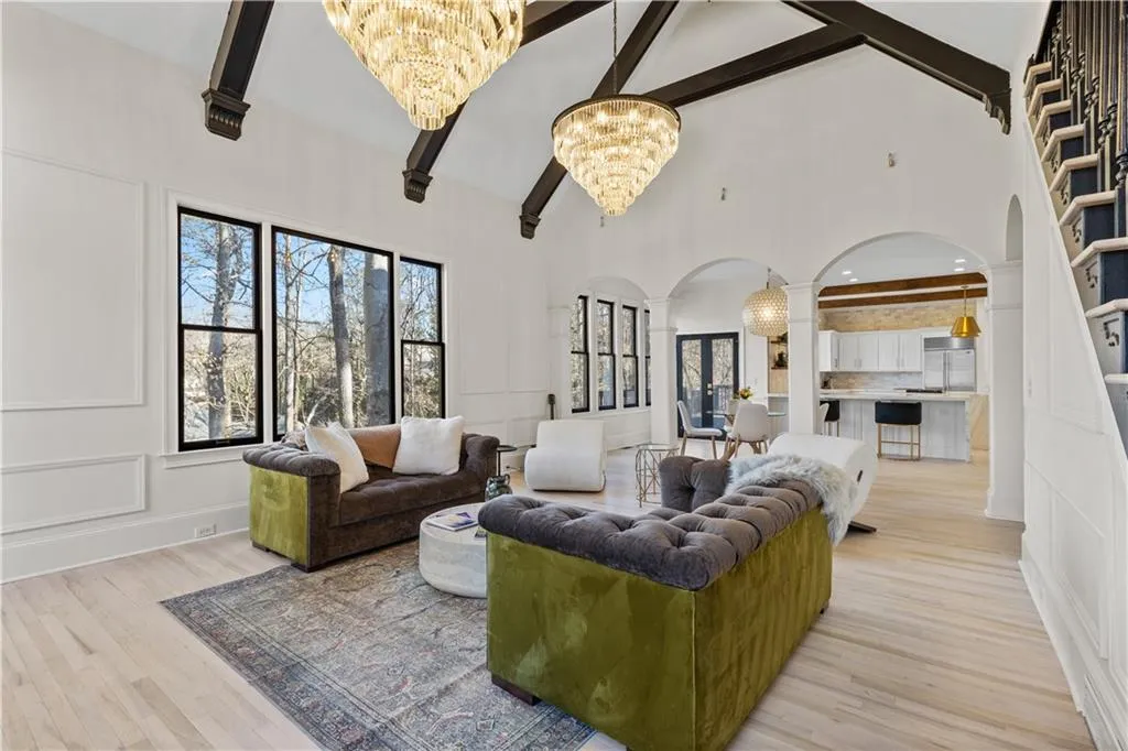 Living area with arched walkways, hanging lights, a decorative wall, plenty of natural light, and lofted ceiling