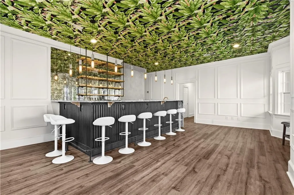 Indoor dry bar featuring a decorative wall, open shelves, and dark wood-style floors