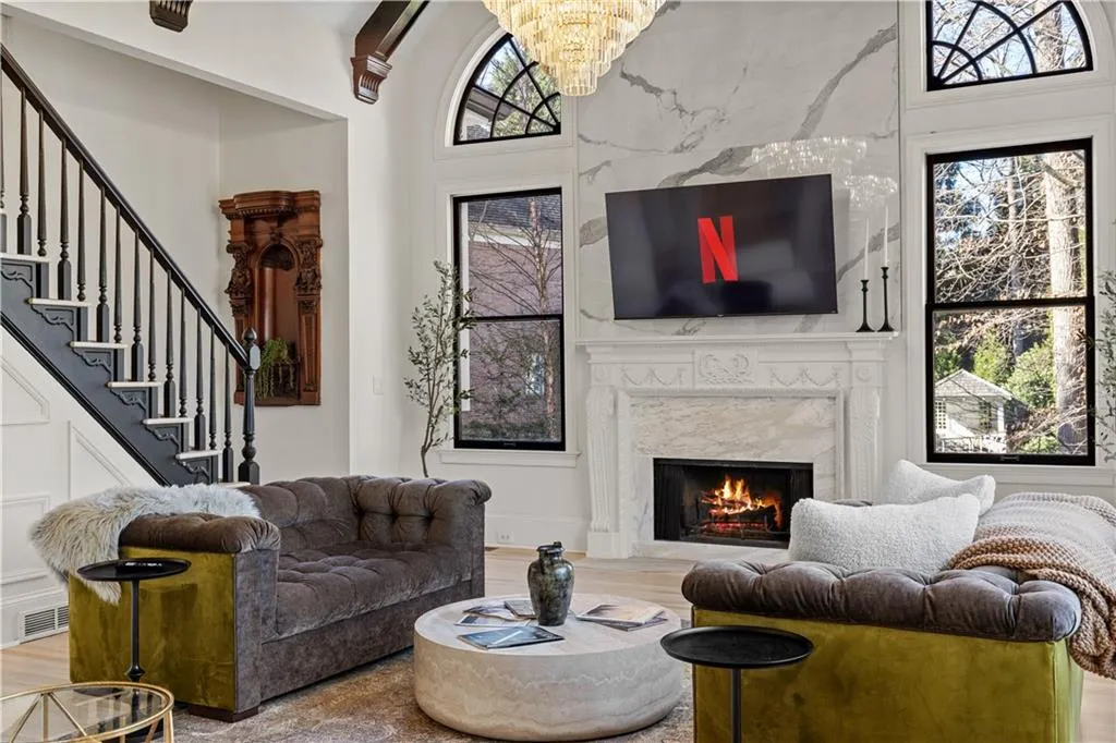 Living area featuring wood finished floors, a high end fireplace, and a chandelier
