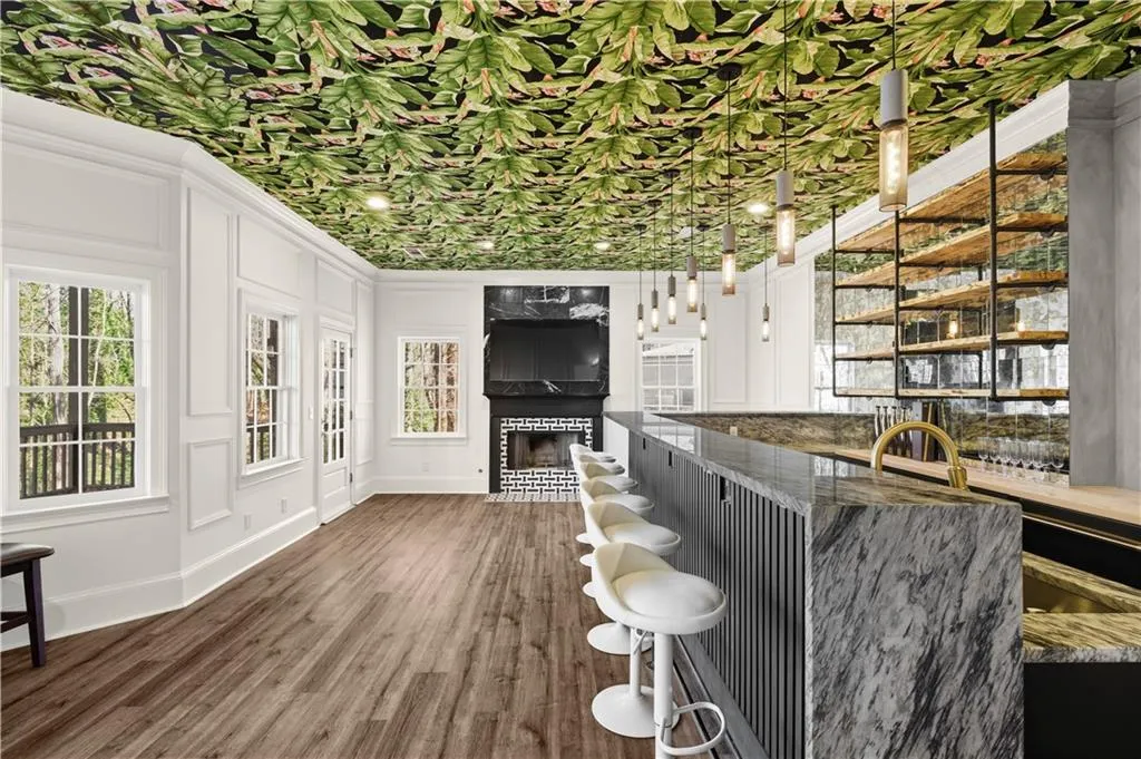 Bar area with healthy amount of natural light, dark wood-style flooring, a fireplace, open shelves, and a decorative wall