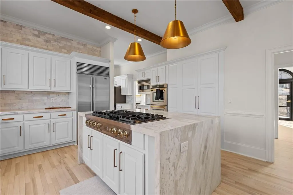 Kitchen featuring crown molding, white cabinets, light wood-type flooring, a kitchen island, and stainless steel appliances