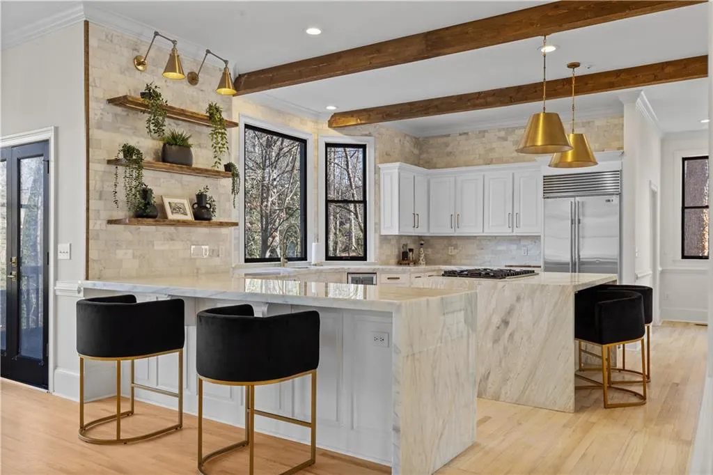 Kitchen with a kitchen bar, ornamental molding, a peninsula, light stone countertops, and healthy amount of natural light
