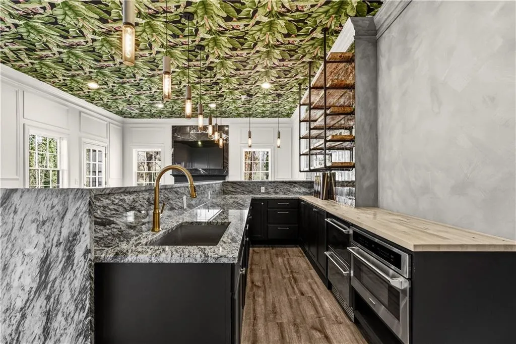 Two tone kitchen with a peninsula, decorative light fixtures, stainless steel oven, dark wood finished floors, and two tone cabinets