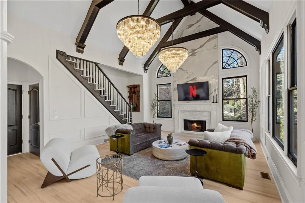 Living room featuring hanging lights, a high end fireplace, light wood-style flooring, a decorative wall, and arched walkways