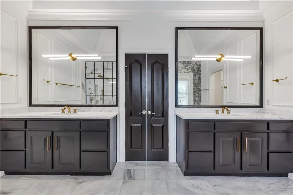 Bathroom featuring light marble finish floors, two vanities, and a closet
